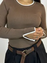 Buzo de punto color marrón con cuello redondo, mangas largas y detalles en color blanco en el cuello y los puños.