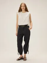 Pantalon negro de lyocell con silueta relajada, bolsillos laterales y detalles de costuras a contraste. Presenta puños ajustables con cordones en los tobillos.