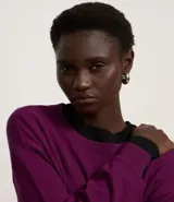 Suéter negro de punto leve, corte boxy, cuello redondo y mangas largas con puños y bajo acanalados.