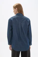 Sobrecamisa de jean en tono celeste claro, con cuello clásico, cierre frontal con botones metálicos y bolsillos frontales tipo parche.
