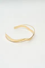 Gargantilla rígida de diseño minimalista en color dorado, compuesta por dos bandas metálicas con forma ondulada que se entrelazan.