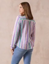 Blusa de lino estampada a rayas verticales en tonos blanco, verde, violeta, amarillo y rosa. Cuello a la base con escote en V y abertura central con botones. Delantera con bolsillos de parche. Mangas largas regulables con presilla y botón.