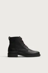 Bota de cuero negro con acabado abatanado, horma cuadrada, cordones rojos en contraste y suela con tacón bloque.