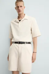 Bermuda de algodón color blanco, de corte relajado, con cintura elástica, bolsillos frontales y bolsillos traseros de plastrón. Cierre frontal con cremallera y botón.