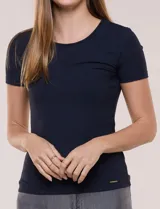 Remera básica de modal elastizado color blanco, con textura acanalada fina, escote redondo y mangas cortas. Presenta un pequeño logo metálico aplicado cerca del ruedo frontal.