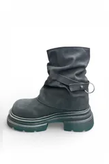 Bota de caña media color negro, con diseño fruncido, suela flatform chunky texturizada y tira decorativa con hebilla en el lateral.