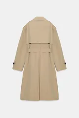 Trench largo de color negro con cuello de solapa, manga larga con trabillas ajustables y cierre frontal cruzado con doble botonadura. Cuenta con bolsillos delanteros de vivo, solapa cortavientos en el pecho y cinturón ajustable del mismo tejido.
