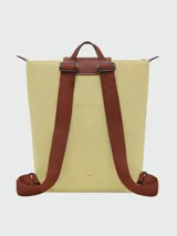 Mochila de diseño minimalista en color beige, con solapa y asa superior en cuero marrón texturizado. Cuenta con correas ajustables en color marrón y cierre principal.