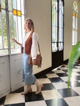 Cartera bandolera de cuero color camel, con forro interno de tela y flecos laterales.