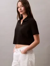 Remera tipo chomba cropped color negro, de algodón acanalado, con cuello polo, cartera abierta y logo bordado en el pecho.