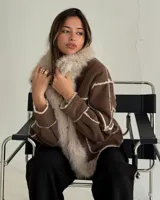 Campera tipo gamulán de cuero marrón con interior y solapas de piel sintética en color crema. Presenta un diseño de paneles con costuras visibles y cierre frontal.