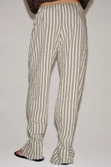 Pantalón de tiro medio con diseño de rayas verticales, confeccionado en mezcla de viscosa. Presenta cintura elástica ajustable con cordones, bolsillos laterales ocultos y pierna recta con bajo ajustable mediante botón.