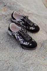 Zapatillas urbanas con capellada de cuero con estampado animal print en blanco y negro, detalles en gamuza negra, cordones negros y suela de goma.