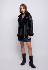 Campera tipo gamulán de cuero sintético negro con interior y solapas de corderito sintético. Presenta cierre frontal metálico, bolsillos laterales con cierre y hebilla ajustable en el cuello.