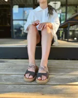 Sandalias bajas de cuero con dos tiras, una de cuero liso color gris y otra con estampado animal print.