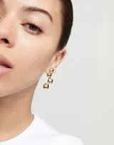 Par de aros colgantes dorados con cuatro esferas de metal cada uno.