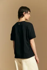 Remera de manga corta color marrón, con cuello redondo y cierre frontal parcial con botones. Presenta un diseño de calce relajado y líneas simples.