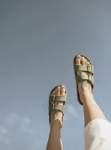 Sandalias planas color ladrillo, con doble tira ancha sobre el empeine y plantilla anatómica. Fabricadas en Brasil con materiales veganos y procesos sostenibles.