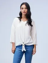 Blusa texturada color blanco, con escote en V con bordado, manga larga de largo regulable y ruedo con nudo.