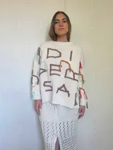 Sweater de punto color marrón con diseño oversize, cuello redondo y mangas largas. Presenta bordados artesanales en relieve con hilos de colores y detalles en lurex, incluyendo flecos decorativos distribuidos por toda la prenda.