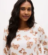 Pijama largo de dos piezas compuesto por una blusa de manga larga con escote redondo y un pantalón con cintura elástica. Presenta un estampado integral de ositos sobre un fondo blanco.