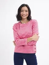 Blusa de manga larga con diseño a rayas horizontales en tonos rosa y rojo. Presenta cuello redondo y detalle de botones decorativos en el lateral inferior.