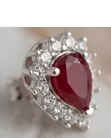 Caravanas de plata 925 con diseño en forma de corazón, presentando una circonia central color rubí rodeada por un marco de pequeñas circonias blancas.