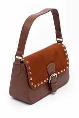 Bolso tipo cartera de mano color marrón, confeccionado en cuerina y gamuza, con solapa frontal decorada con tachas metálicas plateadas y una tira con hebilla central. Cuenta con un asa corta para llevar al hombro.