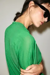 Chaqueta de punto de manga corta y cuello redondo en color verde, con cierre frontal de botones.