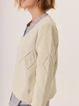 Buzo de lana color marrón topo, con cuello en V y diseño de punto calado en rombos en el frente y mangas.