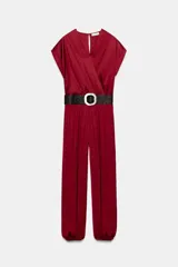 Mono largo satinado de color rojo, con escote en V cruzado y manga corta. Presenta cintura elástica con cinturón negro incorporado, bolsillos laterales ocultos y terminación de las piernas con puño elástico.