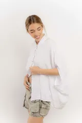 Camisa color crema de lino con mangas amplias y cinta en tono más oscuro en el cuello y la botonadura.