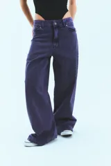 Jean de corte oversized y tiro medio-alto, confeccionado en denim de color violeta con diseño de cinco bolsillos y cierre frontal con botón y cremallera.