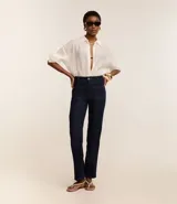 Pantalón de jean azul oscuro, de corte recto y tiro medio. Presenta bolsillos delanteros con costuras contrastantes y cierre frontal con botón y cremallera.