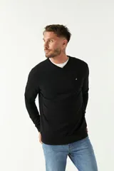 Sweater de punto color negro con escote en V, manga larga y puños acanalados. Presenta un pequeño logo bordado en el pecho.