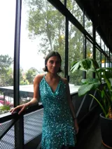 Vestido corto turquesa cubierto de lentejuelas brillantes, con escote en cascada, tirantes que se aten al cuello y volado en el ruedo.