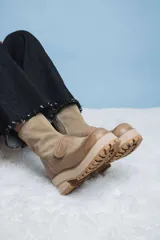 Botas de caña media en combinación de cuero liso y gamuza color visón. Presentan una suela track con plataforma y taco cuadrado, cierre lateral y una tira con velcro sobre el empeine.