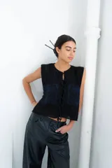 Chaleco de punto calado celeste con diseño estampado en negro y cierre frontal mediante tiras tejidas a crochet.