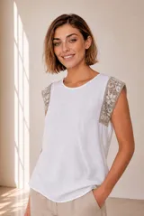 Blusa de lino color beige sin mangas, con cuello redondo y detalles de crochet en los hombros.