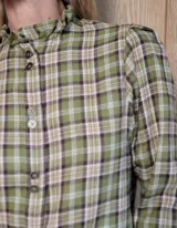 Camisa de manga larga con estampado de rayas verticales en tonos blanco y lila. Presenta cuello alto con volados, cierre frontal con doble botonadura y puños con volados.