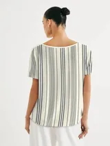 Blusa de manga corta con cuello redondo y estampado de cuadrícula blanca sobre fondo color tostado.