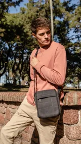 Morral de tela canvas color negro, con tapa frontal, múltiples bolsillos con cierre y correa larga regulable.