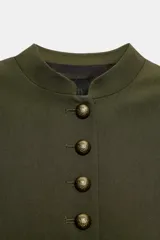 Cazadora militar de color verde oscuro, de cuello subido y manga larga. Cuenta con detalles de alamares y cordones dorados en los hombros y puños, y cierre frontal con botones dorados metálicos.