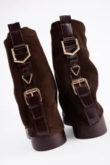 Bota de caña media confeccionada en cuero vacuno color marrón oscuro, con diseño de pliegues en la caña y suela de goma al tono con textura estriada.