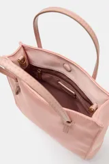 Bolso de mano mini shopper en color rosado con efecto satinado. Cuenta con doble asa de mano y cierre imantado.