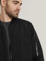 Campera bomber negra Calvin Klein con diseño acolchado en forma de rombos, cierre frontal con cremallera, cuello, puños y dobladillo acanalados, bolsillos laterales y bolsillo con cremallera en la manga izquierda.