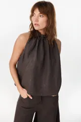 Blusa de lino italiano color marrón oscuro, con corte en línea A, hombros descubiertos, escote halter con frunces y volado en el cuello.