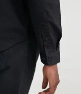 Camisa verde militar de manga larga en sarga de algodón, con cuello clásico, cierre frontal abotonado y dos bolsillos con solapa abotonada en el pecho.