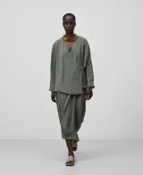 Falda midi color verde oliva con textura arrugada, corte pareo y cierre lateral con cremallera.