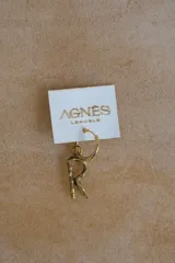 Aro tipo argolla con dije colgante en forma de letra, fabricado en bronce. Se vende por unidad.